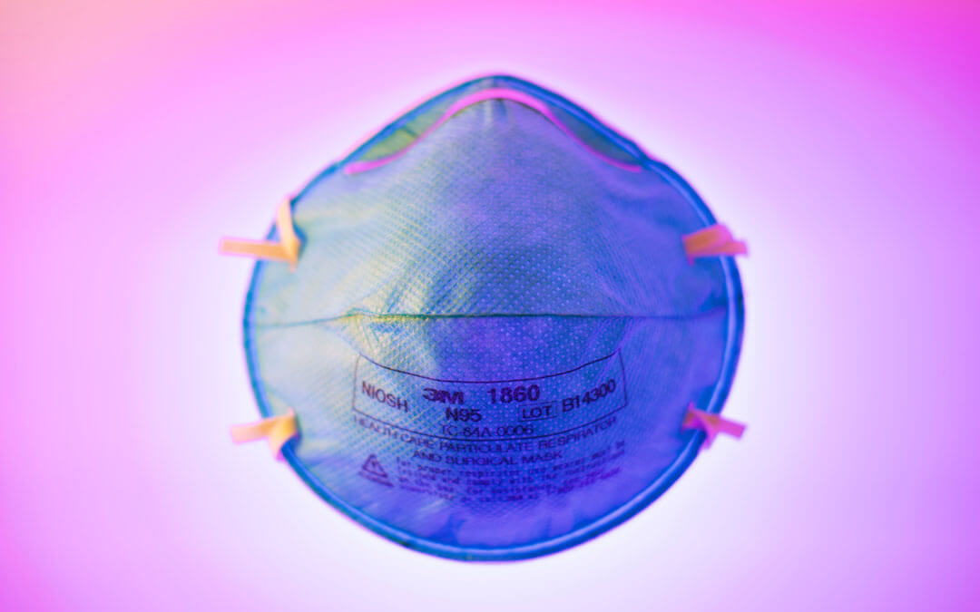 Close up of an N-95 mask on a pinkish background.