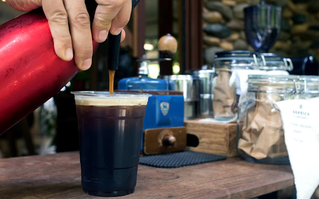 Barista is forcing nitrogen into the the coffee.Sparkling Nitro Cold Brew Coffee on wood table outdoor coffee café.