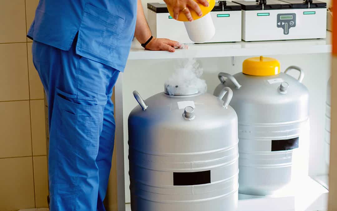 Closeup of technician taking a cryo sample out of Liquid Nitrogen cryo storage in laboratory.