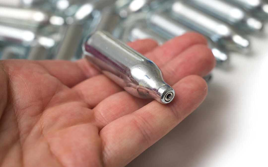 A small nitrour oxide cylinder rests on a hand.