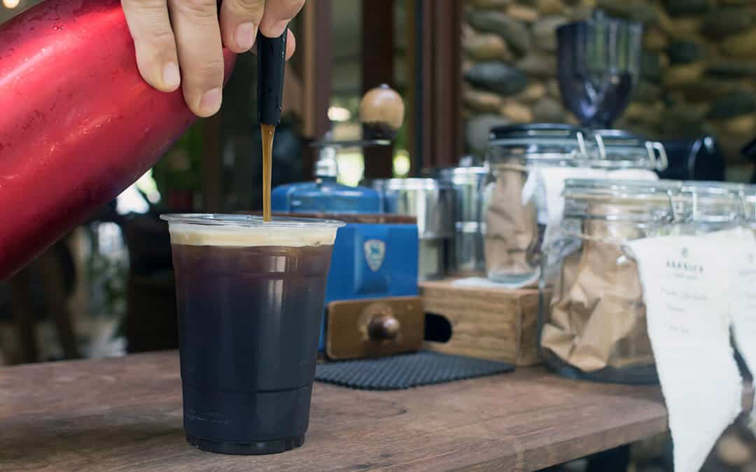 Barista is forcing nitrogen into the the coffee.Sparkling Nitro Cold Brew Coffee on wood table outdoor coffee café