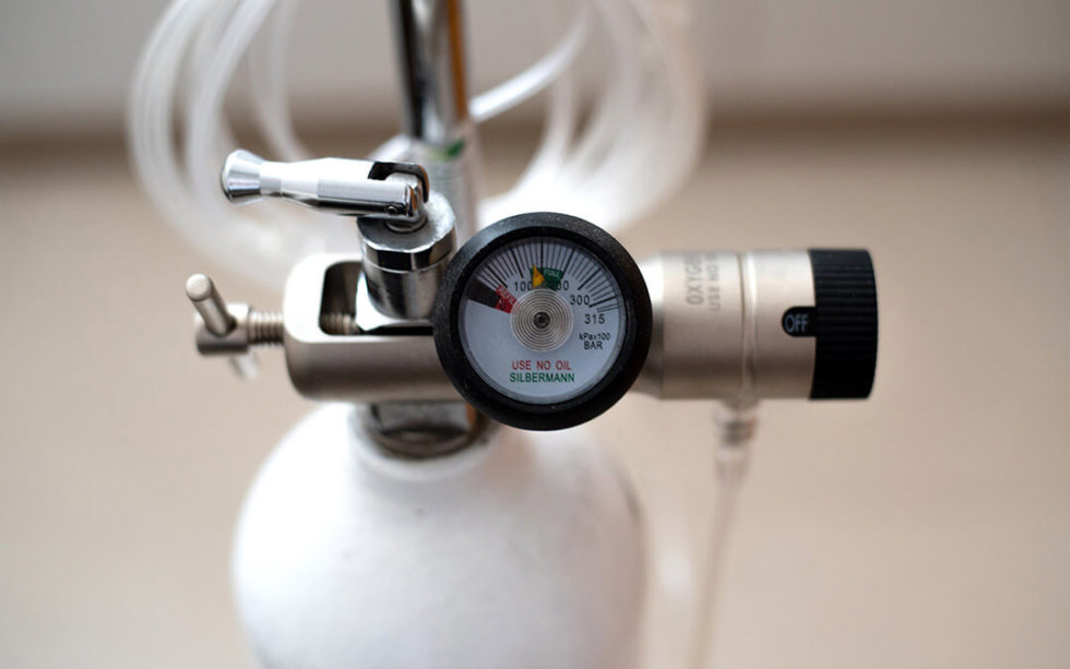 How do pressure regulators work with medical gas cylinders