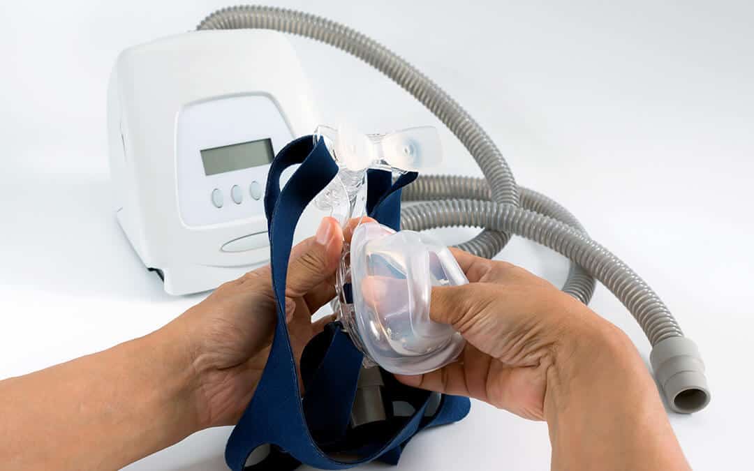 A pair of hands holding the tube and mask for a CPAP machine.