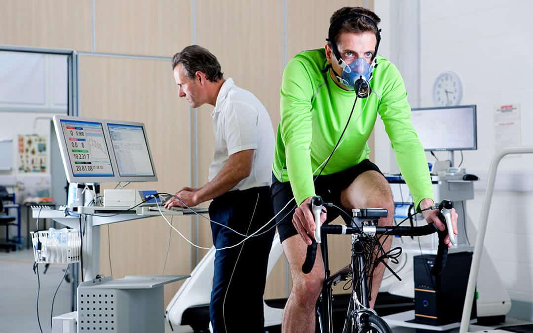 Sports scientist recording the performance of a cyclist working out on the exercise bike