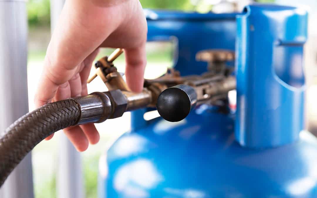 Man filling up a blue gas cylinder.