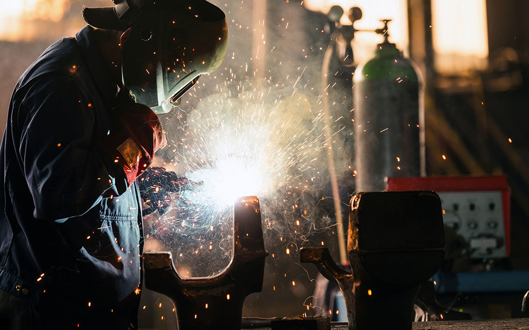A welder performing work. Gas tank in the background.
