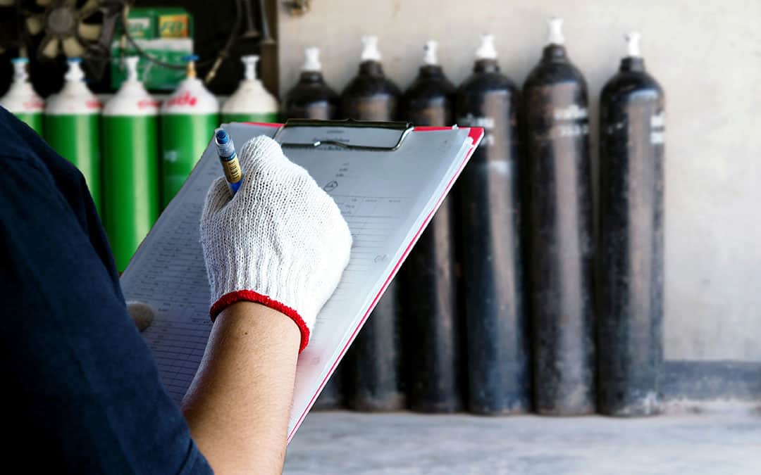 technician with a checkboard in hand, checking a row of Oxygen tanks