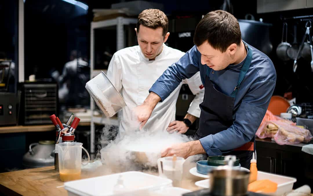Two chefs preparing food using liquid nitrogen