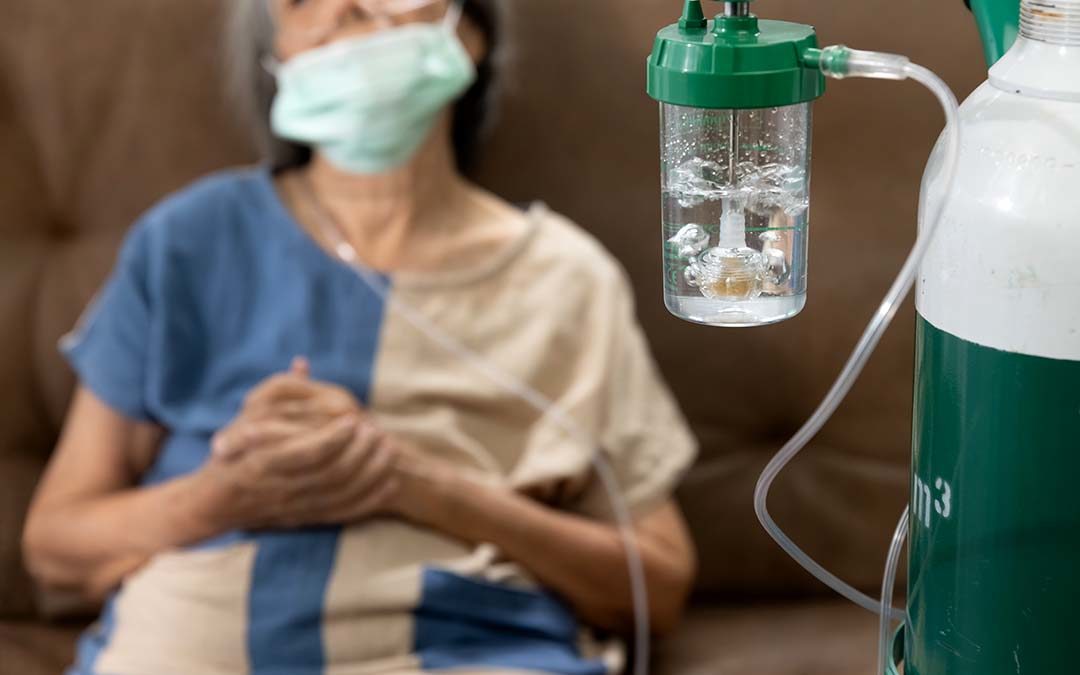 Woman sitting with nose tubes connected to oxygen tank