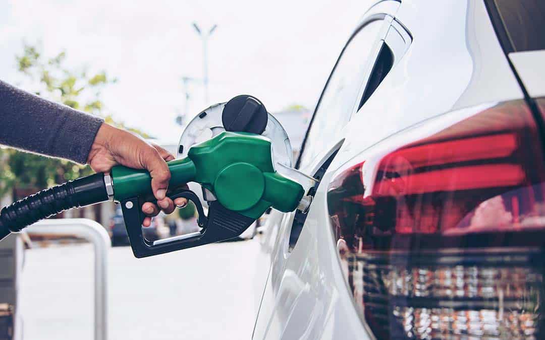 A hand putting a gas pump into a car