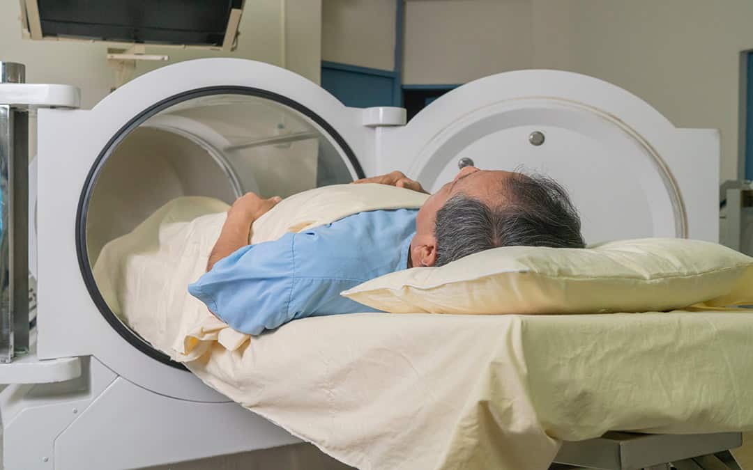 Hyperbaric Oxygen Therapy - Older man lying on a stretcher starting treatment in the hyperbaric machine tube.