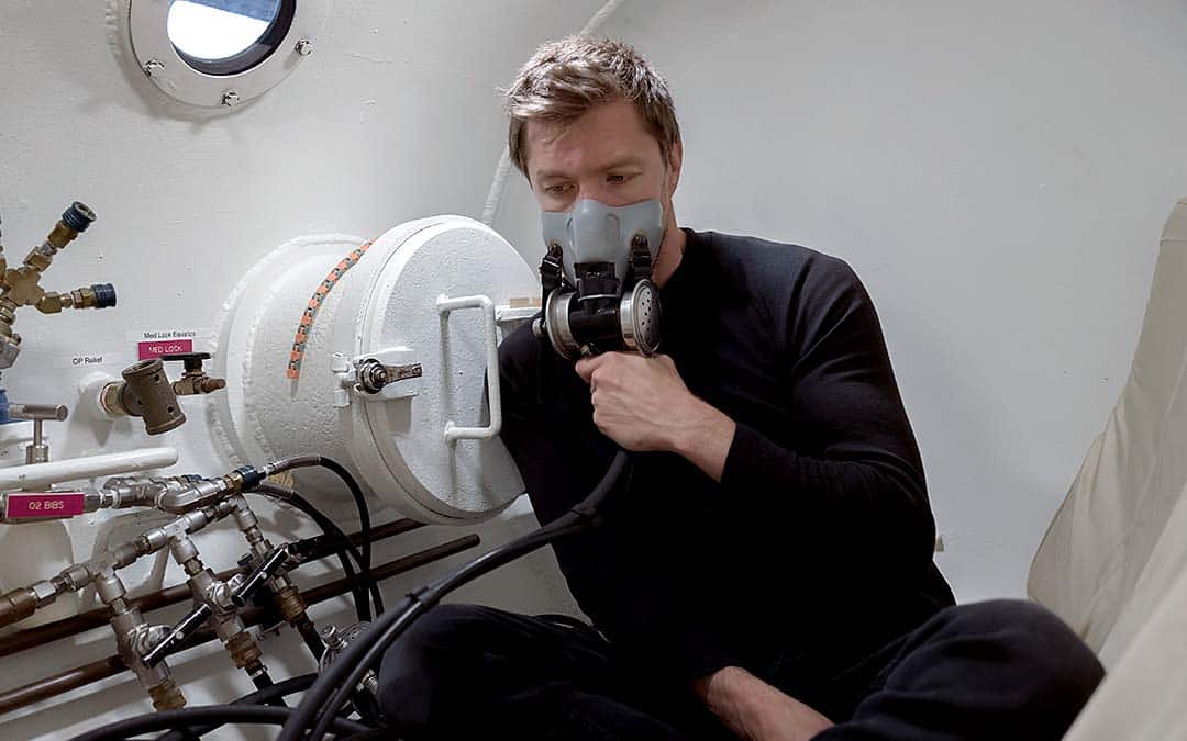 Man with oxygen mask on in Hyperbaric Oxygen Therapy