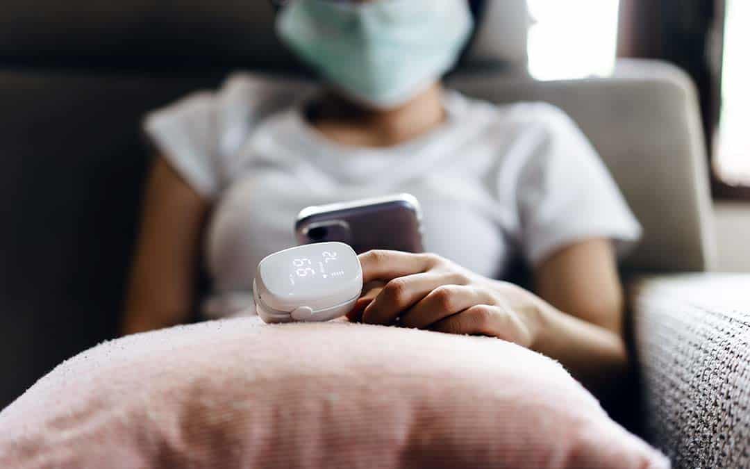 woman holding mobile phone with a pulse oximeter on her finger